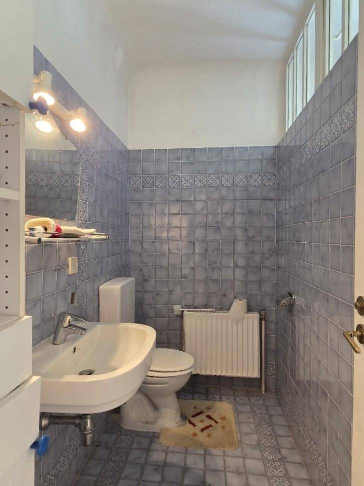 Gäste-WC mit blauen Fliesen, Waschbecken und Fenster.