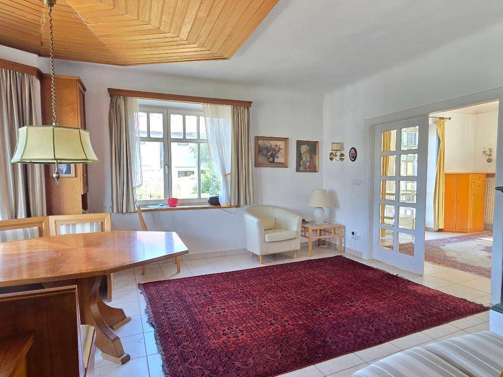 Esszimmer mit Holztisch, Fliesenboden und Übergang zum Wohnbereich.