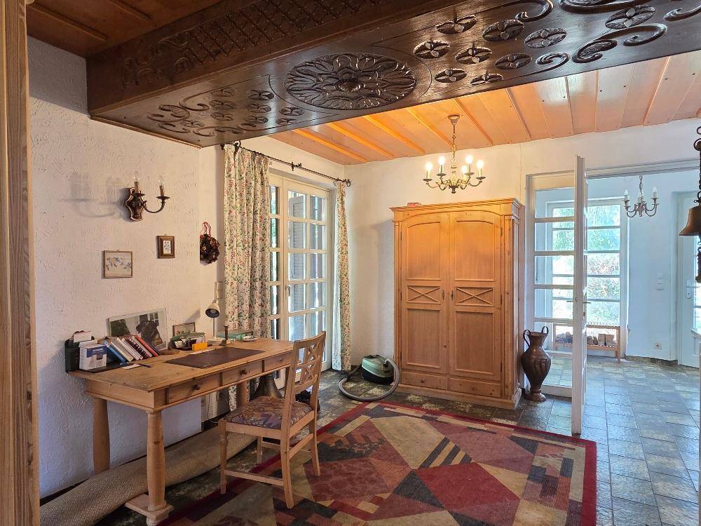 Arbeitszimmer mit Holzboden, geschnitzter Holzdecke und Zugang zum Garten.