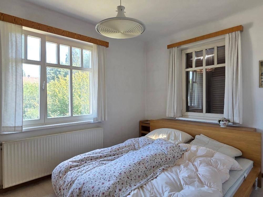 Gemütliches Schlafzimmer mit Holzbett, Teppichboden und Blick ins Grüne.