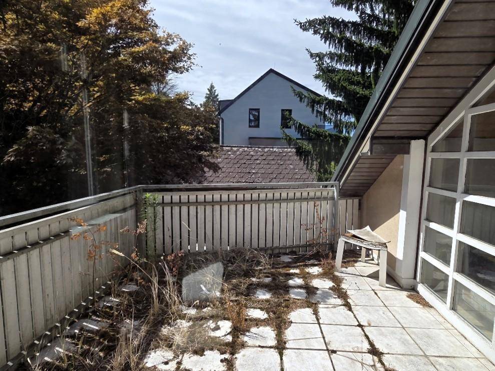 Renovierungsbedürftiger Balkon mit Holzboden und Blick auf die Umgebung.