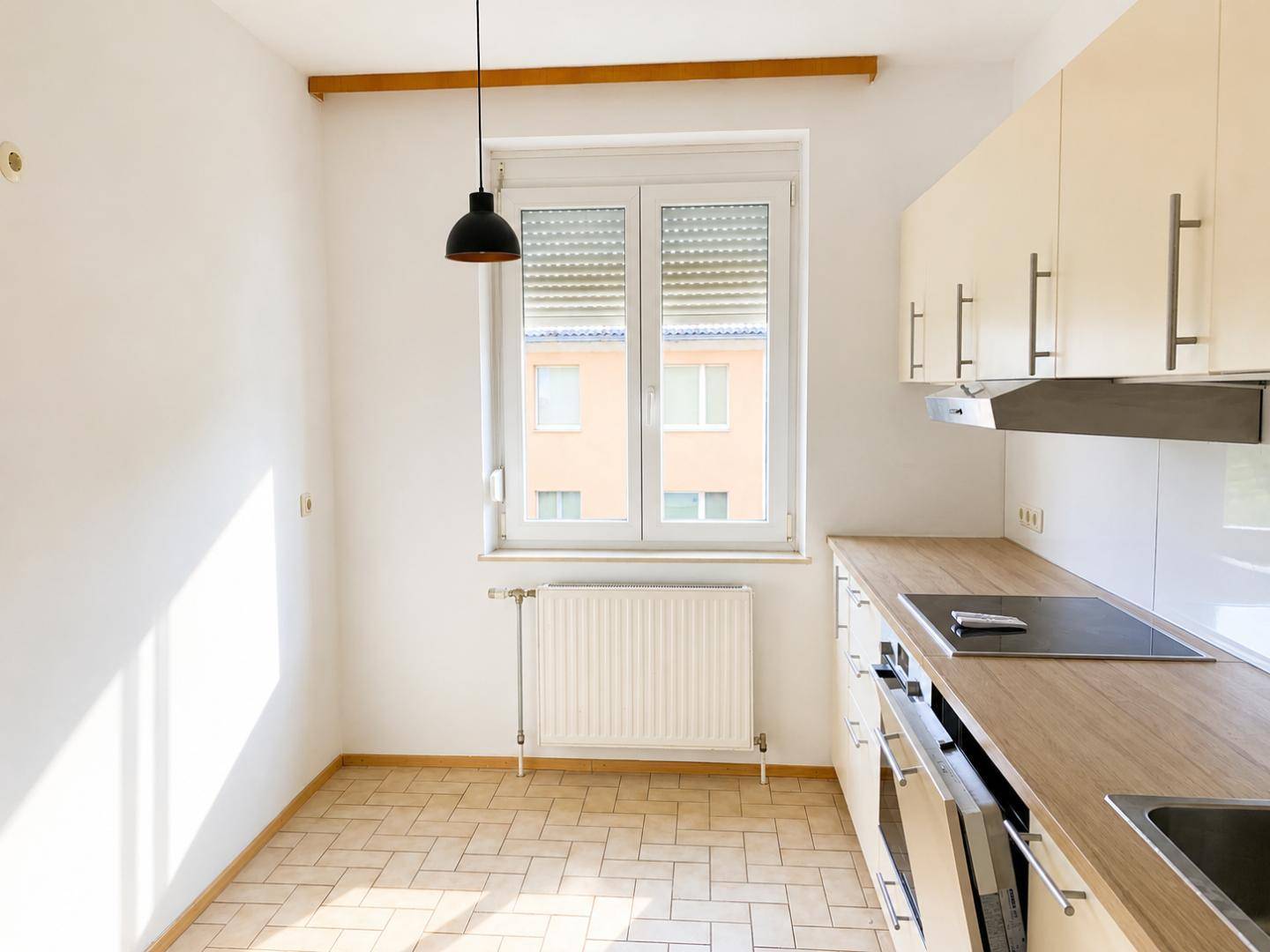 Funktionale Küche mit hellen Schränken, Holzarbeitsplatte und Induktionskochfeld.