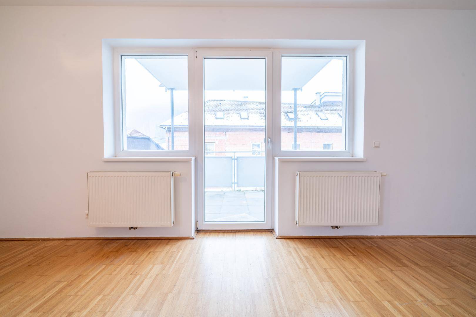 Große Fensterfront mit Balkontür, die viel Tageslicht in den Wohnbereich lässt.
