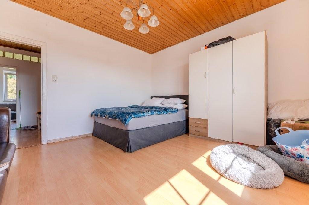 Schlafzimmer mit Doppelbett, weißem Kleiderschrank und warmer Holzdecke, bietet einen gemütlichen Rückzugsort.