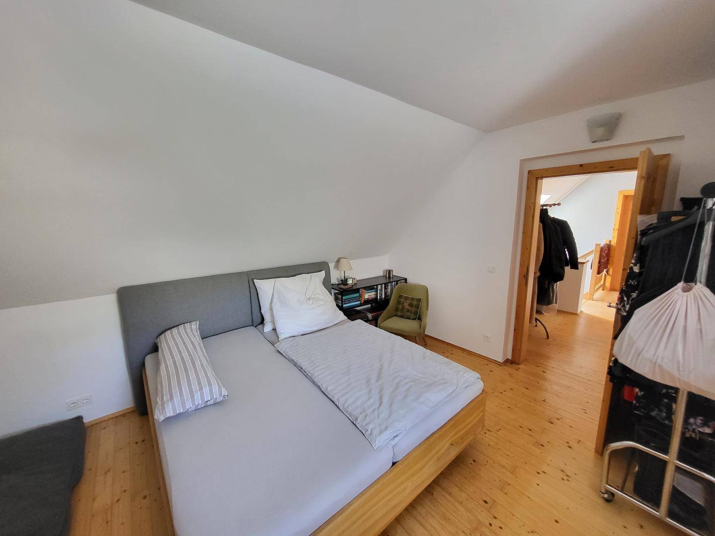 Schlafzimmer mit Doppelbett, Dachschräge und hellem Holzfußboden, bietet einen ruhigen Rückzugsort.