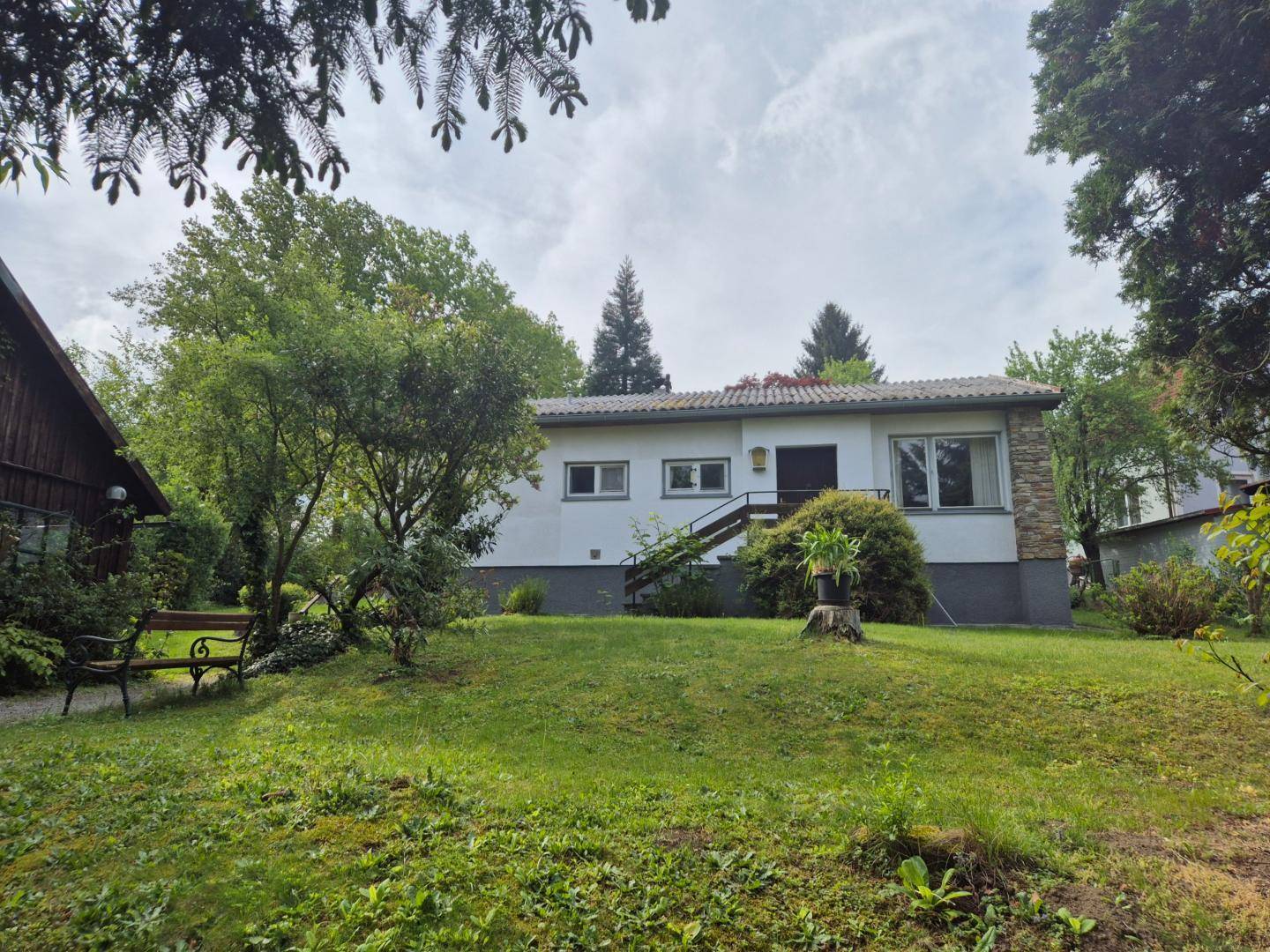 Gepflegter Garten mit Rasenfläche und einem Einfamilienhaus im Hintergrund.