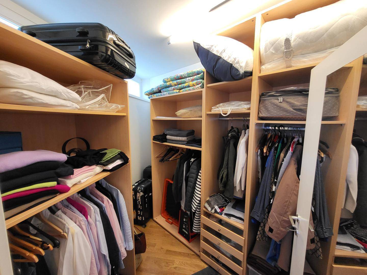 Geräumiger begehbarer Kleiderschrank mit vielen Regalen und Aufbewahrungsmöglichkeiten.