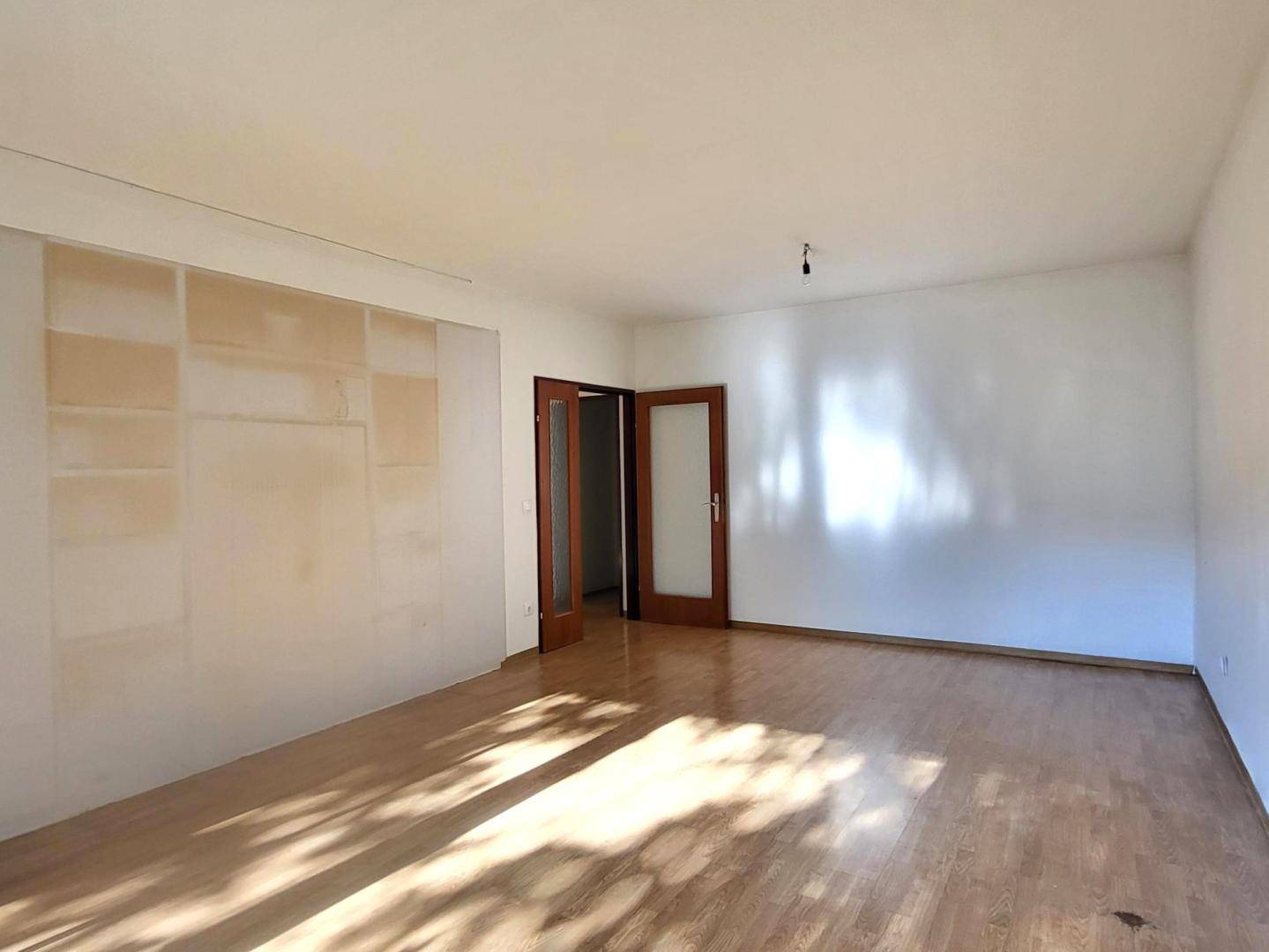 Geräumiges, helles Zimmer mit Holzfußboden und einer Wandnische, die auf Fertigstellung wartet.