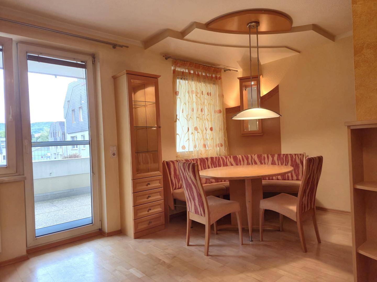 Gemütlicher Essbereich mit runder Holztafel, Eckbank und Zugang zum Balkon.