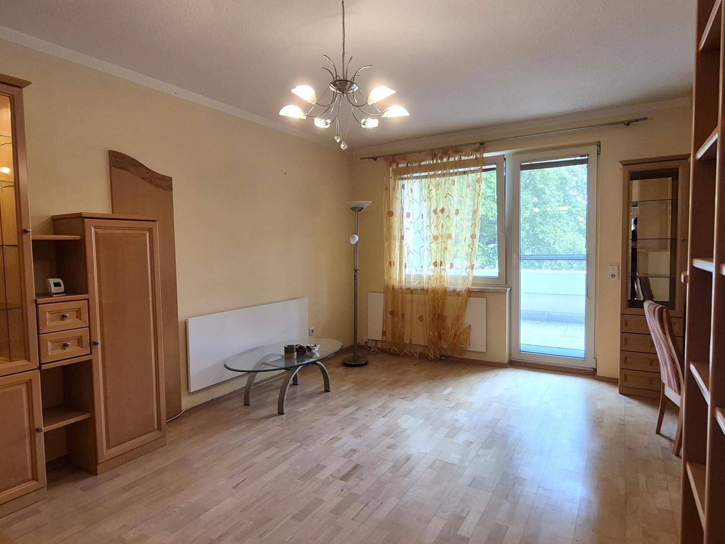 Helles Wohnzimmer mit Parkettboden, großem Fenster und Balkonzugang.