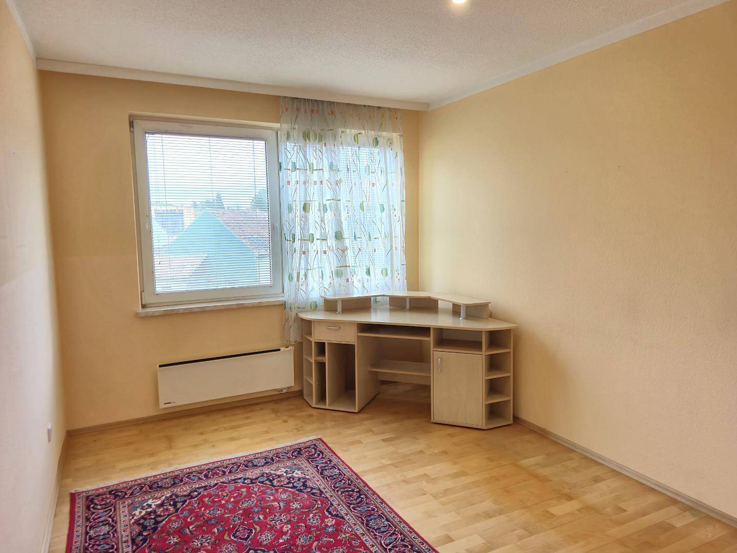 Helles Zimmer mit Schreibtisch, Fenster und Parkettboden, ideal als Arbeitszimmer.