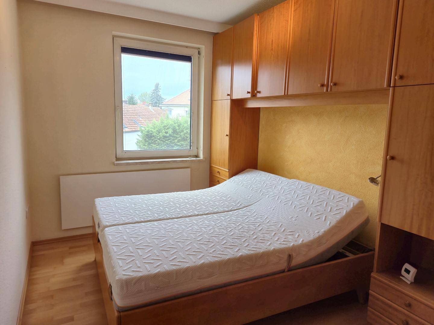 Schlafzimmer mit Doppelbett, Einbauschränken aus Holz und Fensterblick.