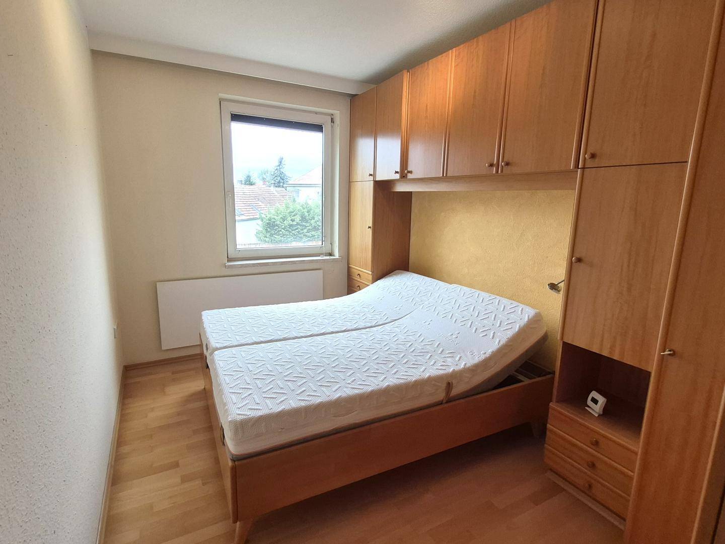Gemütliches Schlafzimmer mit integrierten Holzschränken und hellem Fenster.