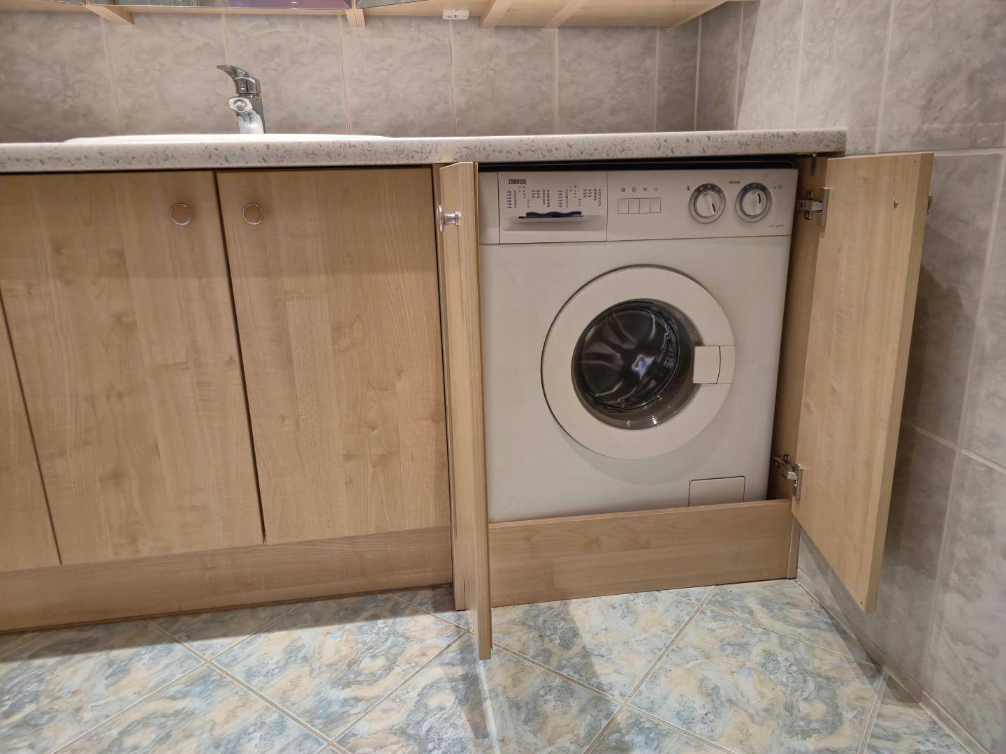 Waschmaschine unter einer Arbeitsplatte in einem funktionalen Bereich.