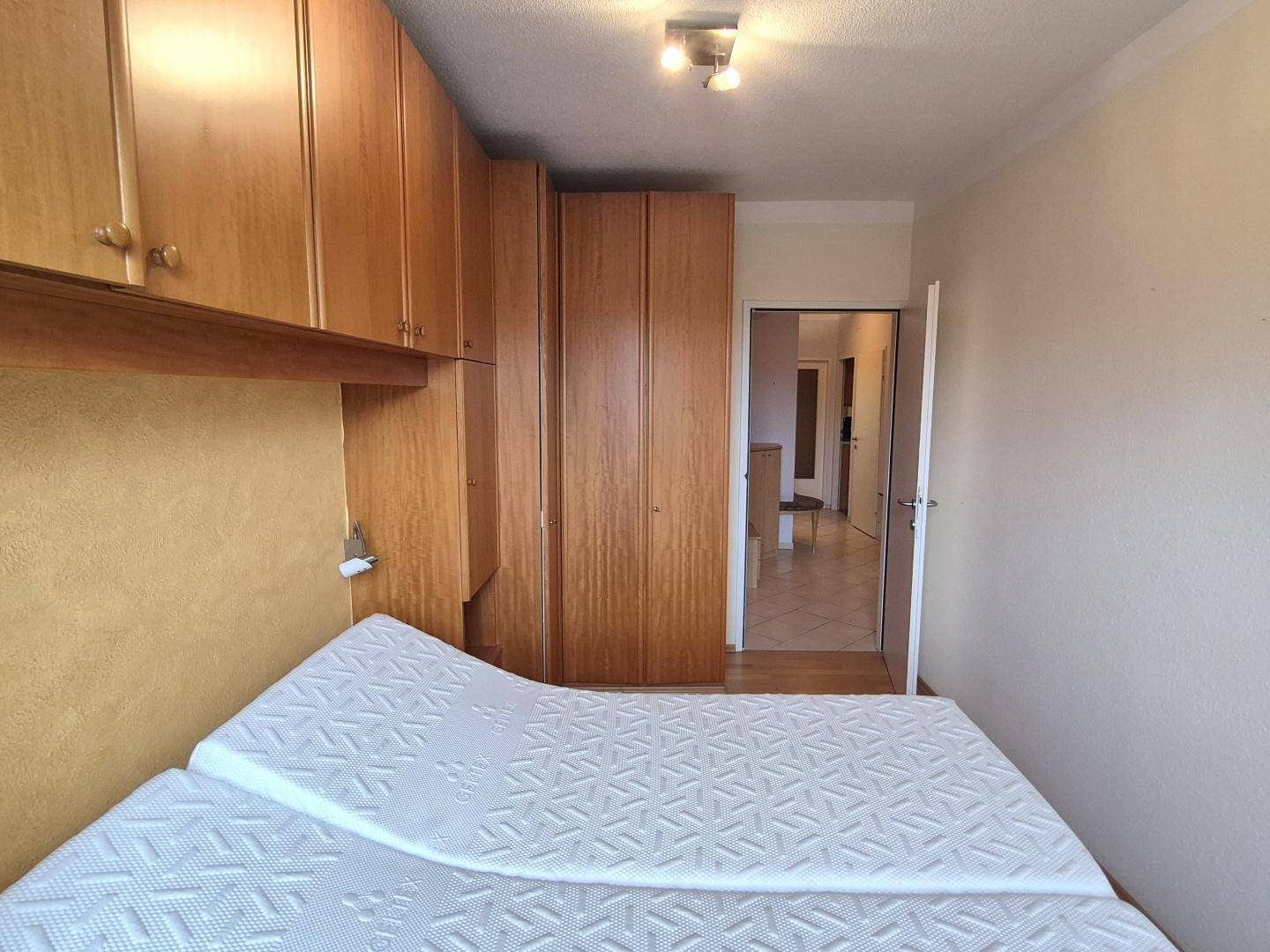 Schlafzimmer mit Doppelbett, Einbauschränken aus Holz und Zugang zum Flur.