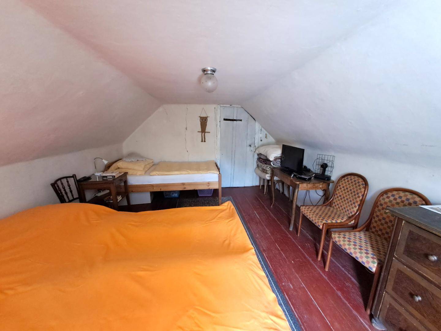Gemütliches Schlafzimmer im Dachgeschoss mit schrägen Wänden und Holzboden.