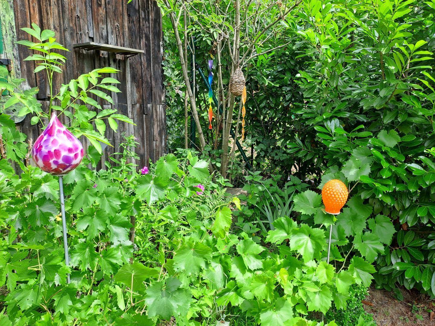Grüner Gartenbereich mit üppiger Vegetation und dekorativen Elementen.
