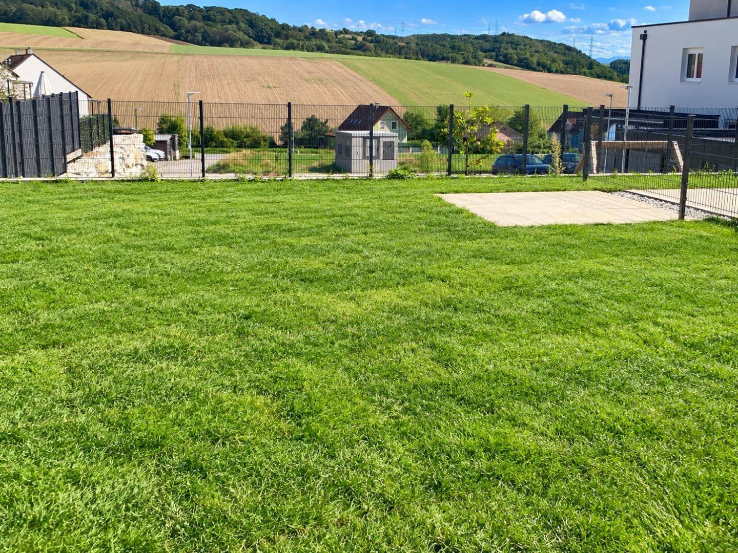 Weitläufiger Gartenbereich mit Rasenfläche und Blick auf die umliegende Natur und Felder.