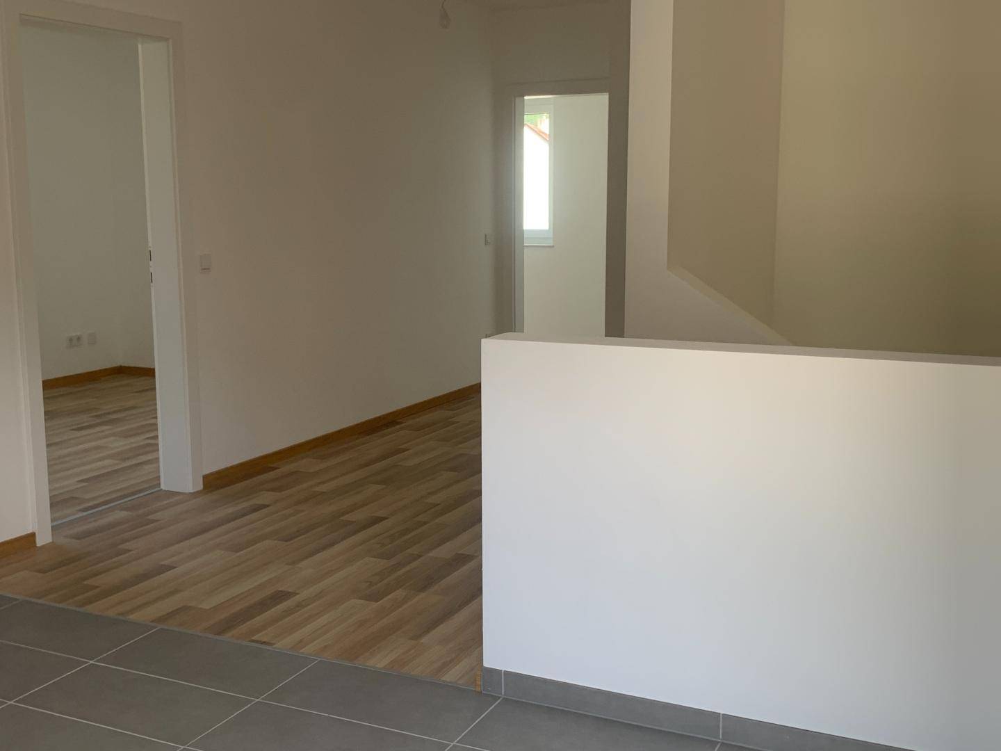 Heller Flur mit Fliesenboden im Eingangsbereich und Laminat in den angrenzenden Räumen.
