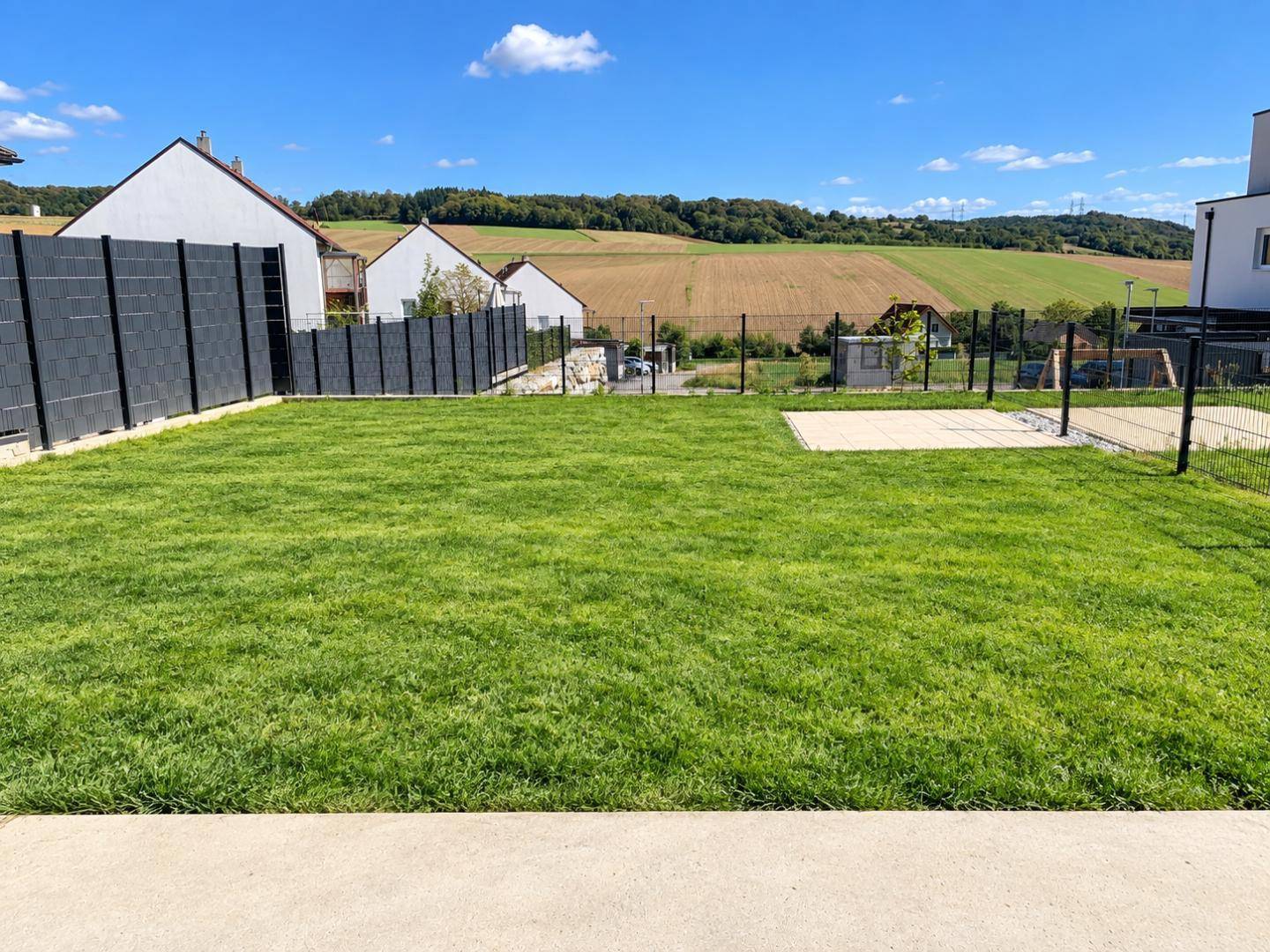 Gepflegter Gartenbereich mit Rasenfläche und weitem Blick über die Felder und Hügel.