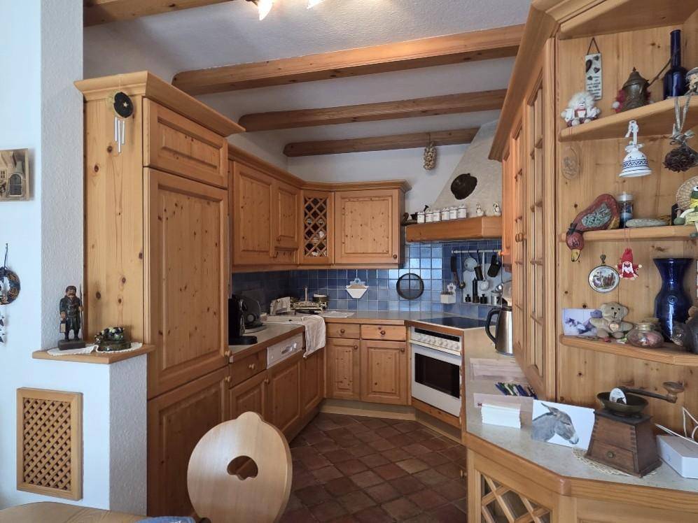 Rustikale Holzküche mit Terrakottafliesen und sichtbaren Deckenbalken, traditionell eingerichtet.