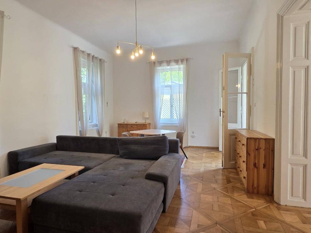 Heller Wohnbereich mit bequemer Sitzecke und Esstisch, durch große Fenster lichtdurchflutet.