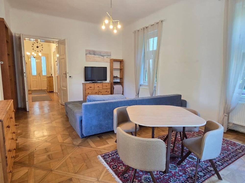 Gemütlicher Wohn-Essbereich mit Fischgrätparkett, großem Sofa und Esstisch, offen zum Flur.