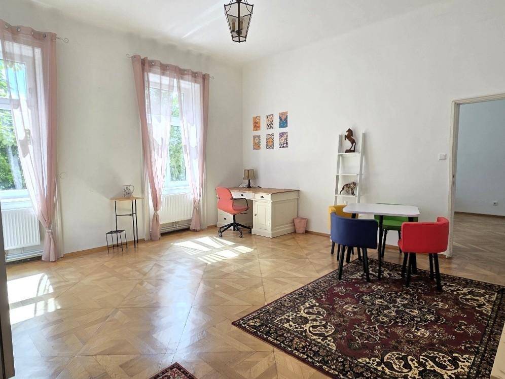 Helles Zimmer mit Fischgrätparkett, Schreibtisch und farbenfrohen Stühlen, ideal als Büro oder Kinderzimmer.