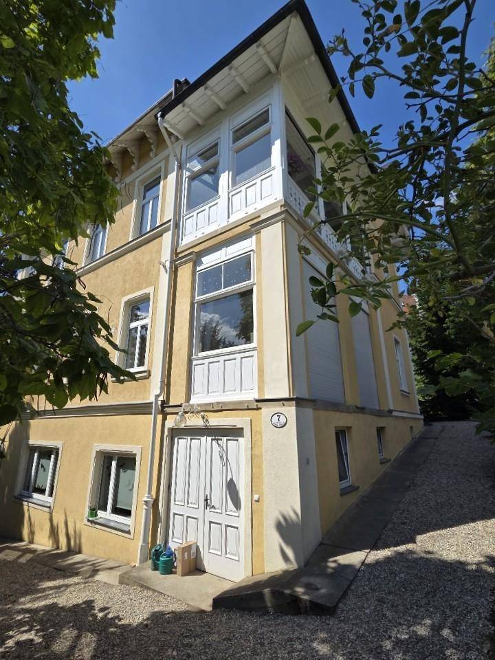 Gebäudeecke mit gelber Fassade, Rampe zum Eingang und mehreren Fenstern.
