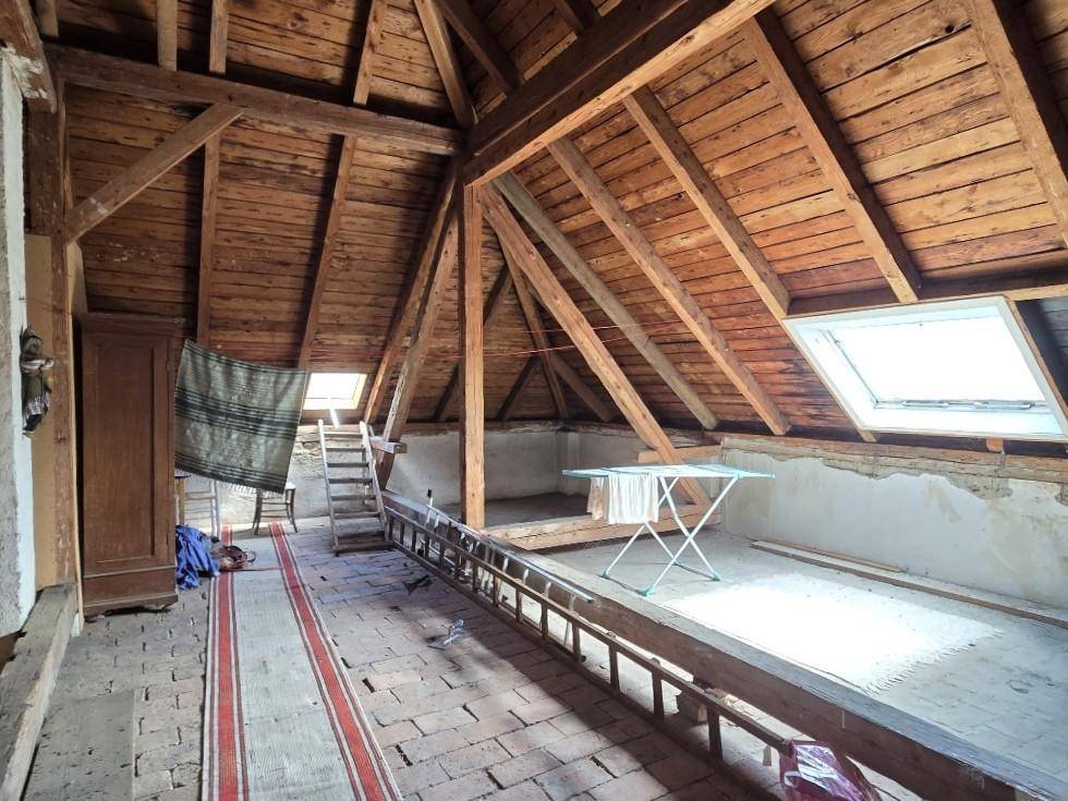 Rustikaler Dachboden mit sichtbaren Holzbalken und Dachfenster, bietet Ausbaupotenzial.