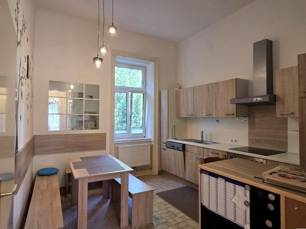 Funktionale Küche mit hellen Holzfronten, Essbereich und Fenster für Tageslicht.