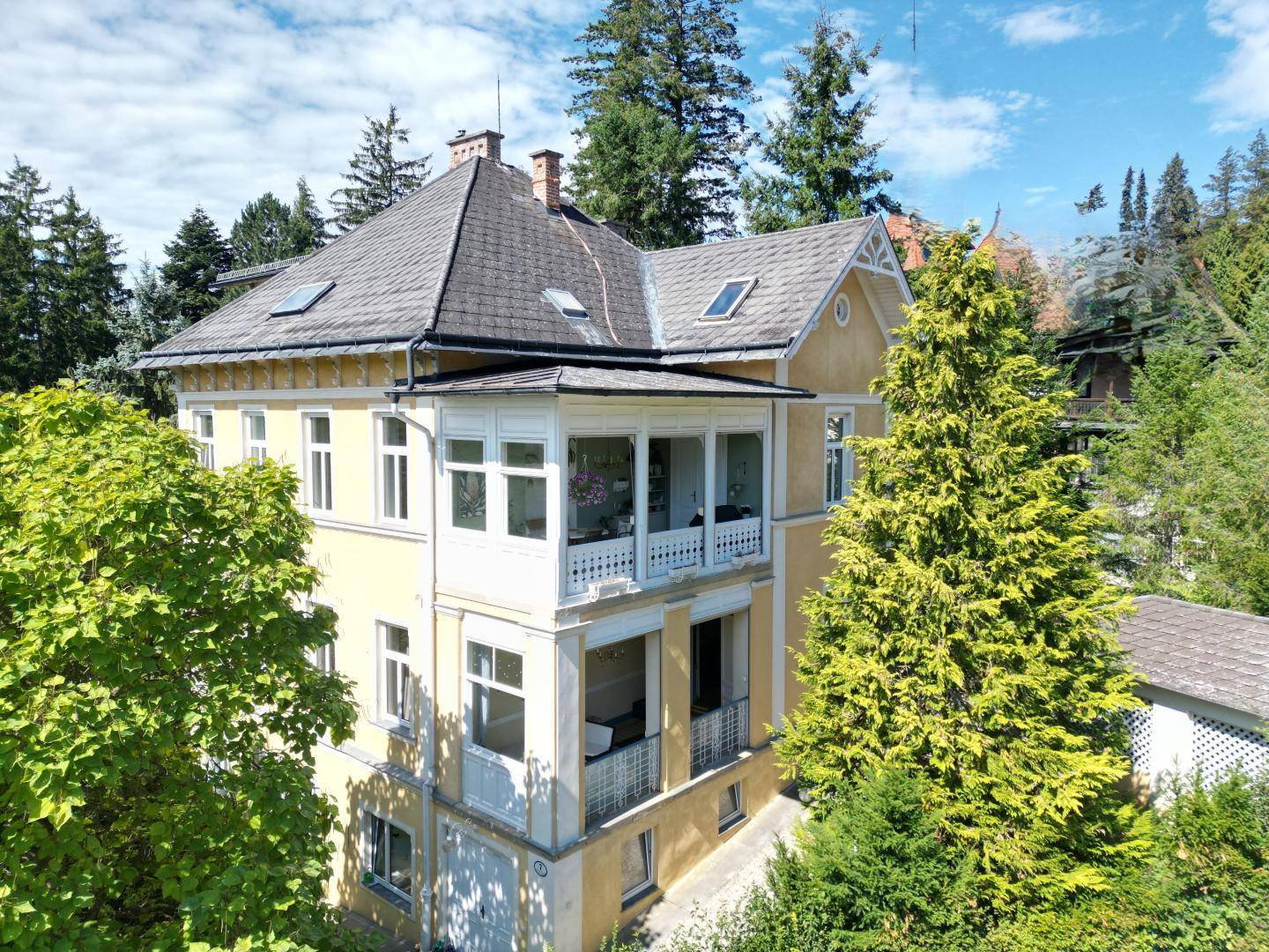 Ansicht der charmanten Villa mit ihren charakteristischen Balkonen und der umgebenden Natur.