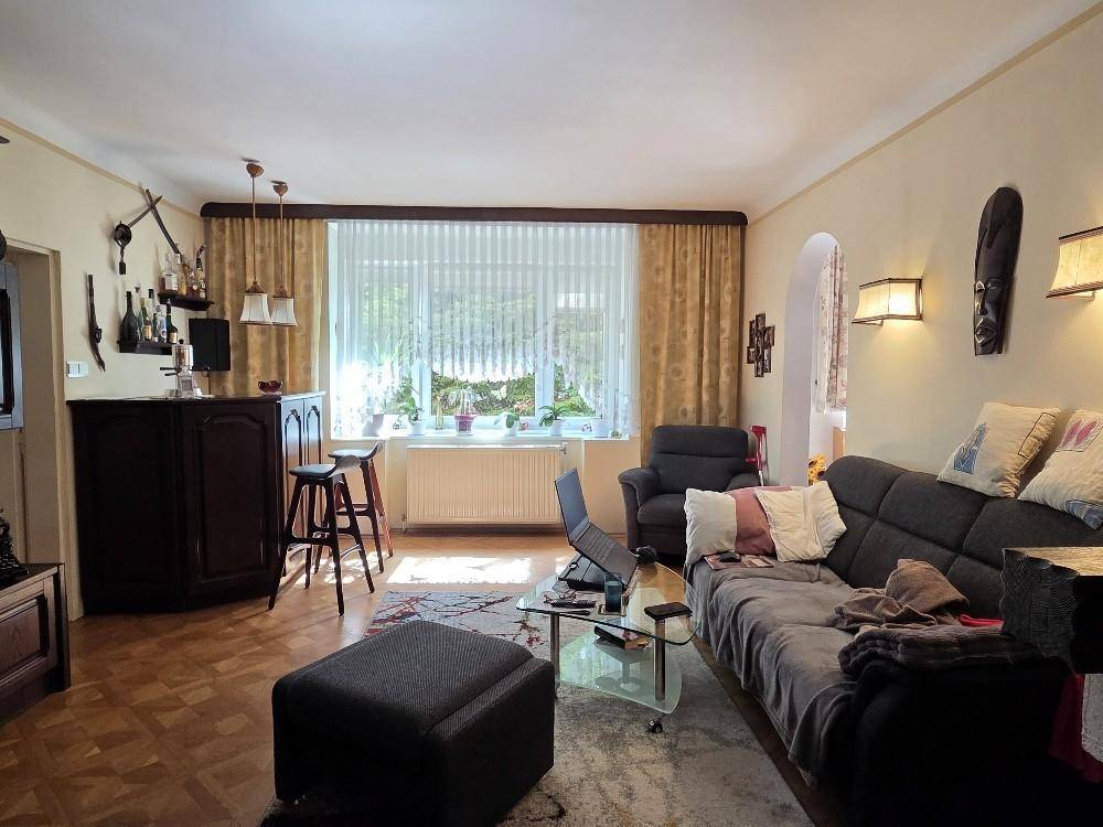 Helles Wohnzimmer mit Parkettboden, Sofa, Couchtisch und einer kleinen Bar.