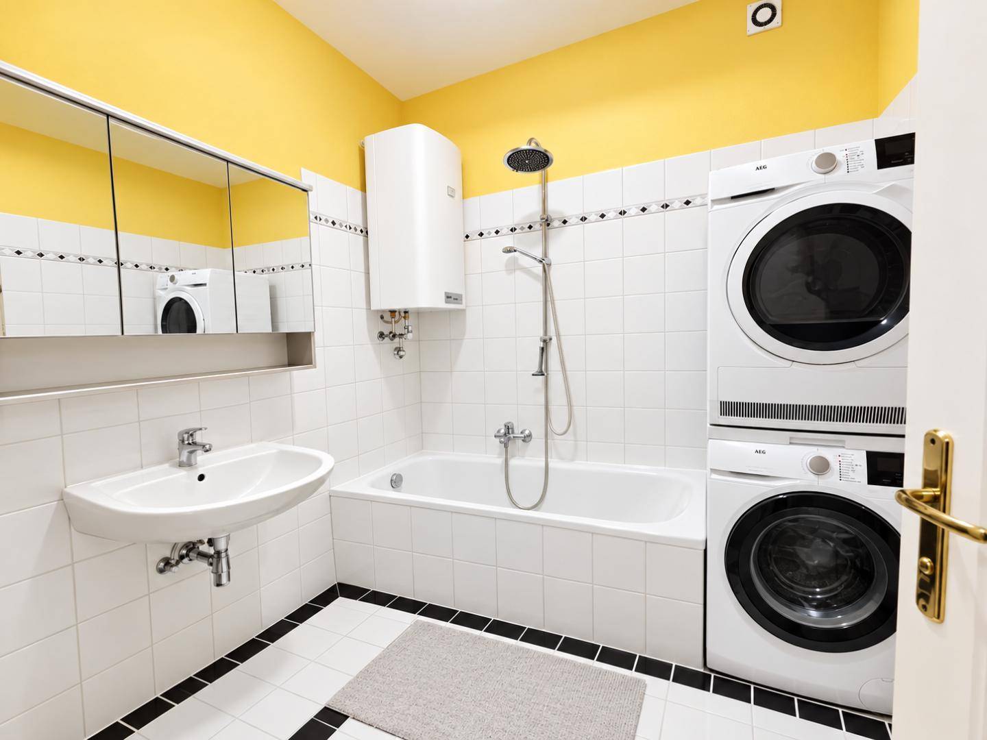 Badezimmer mit Badewanne, Waschbecken, Spiegelschrank und Waschmaschine mit Trockner.