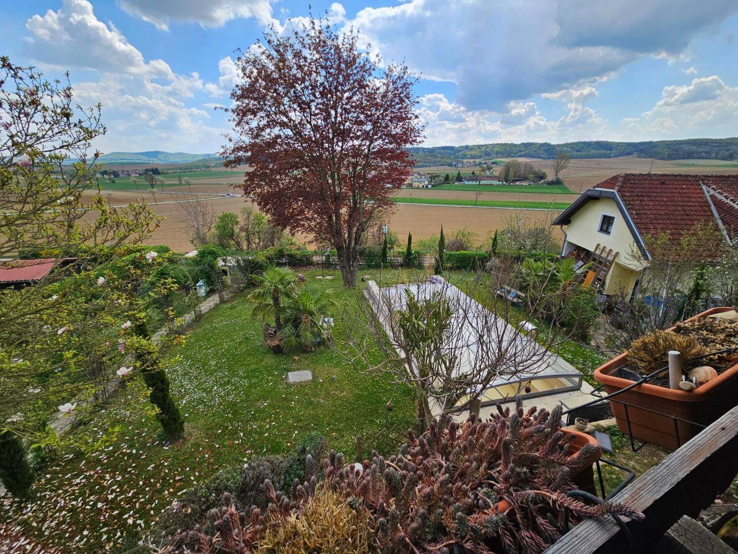 Weitläufiger Garten mit Pool, Rasenfläche und Blick auf die umliegende Landschaft.