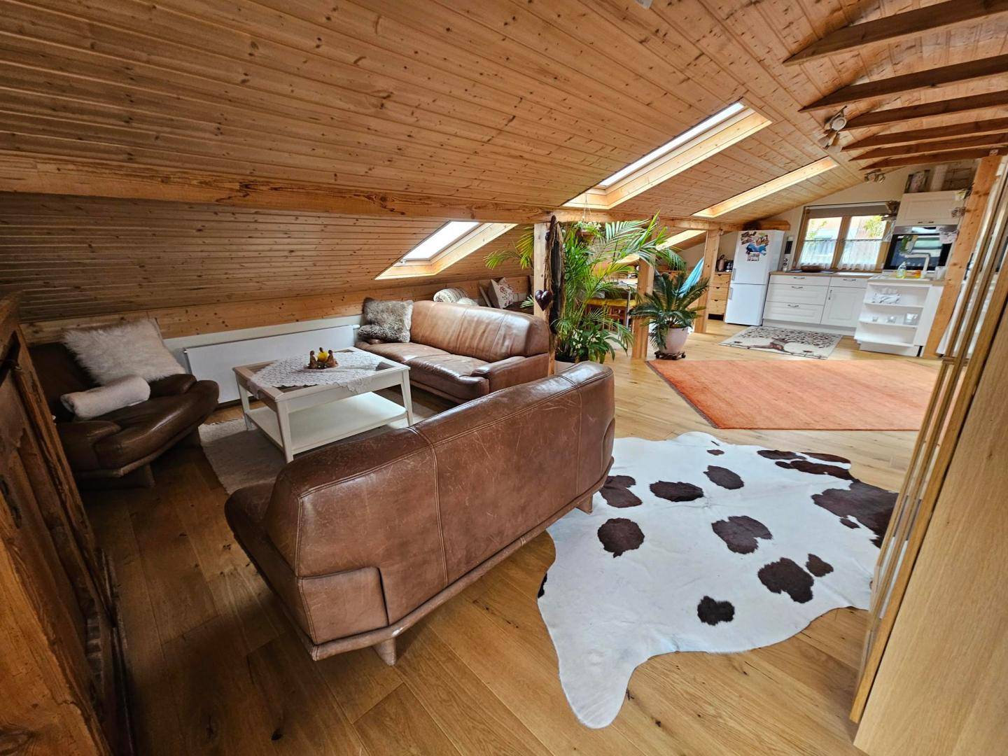 Geräumiger Wohnbereich im Dachgeschoss mit Ledersofas, Holzboden und rustikalen Akzenten.