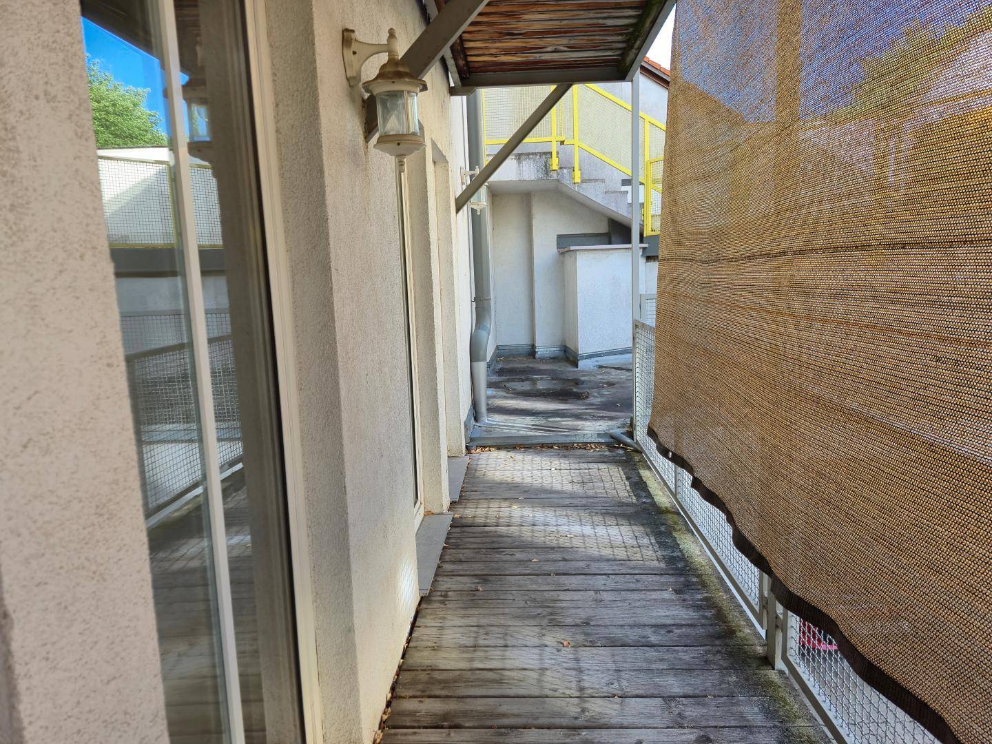 Schmaler Balkon mit Holzbelag und Sichtschutz, ideal für entspannte Stunden.