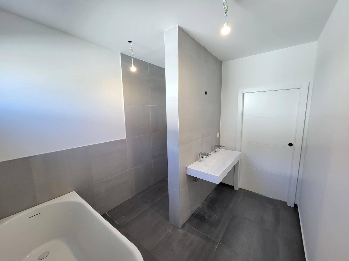 Geräumiges Badezimmer mit Badewanne, begehbarer Dusche und modernem Waschbecken.