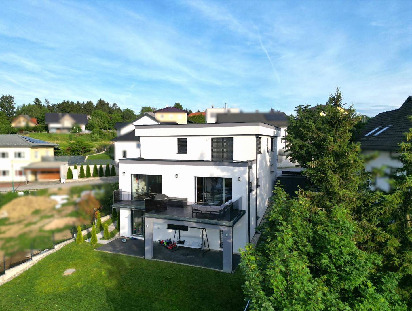 Ansicht des modernen Hauses von oben mit umliegender grüner Landschaft und Bäumen.