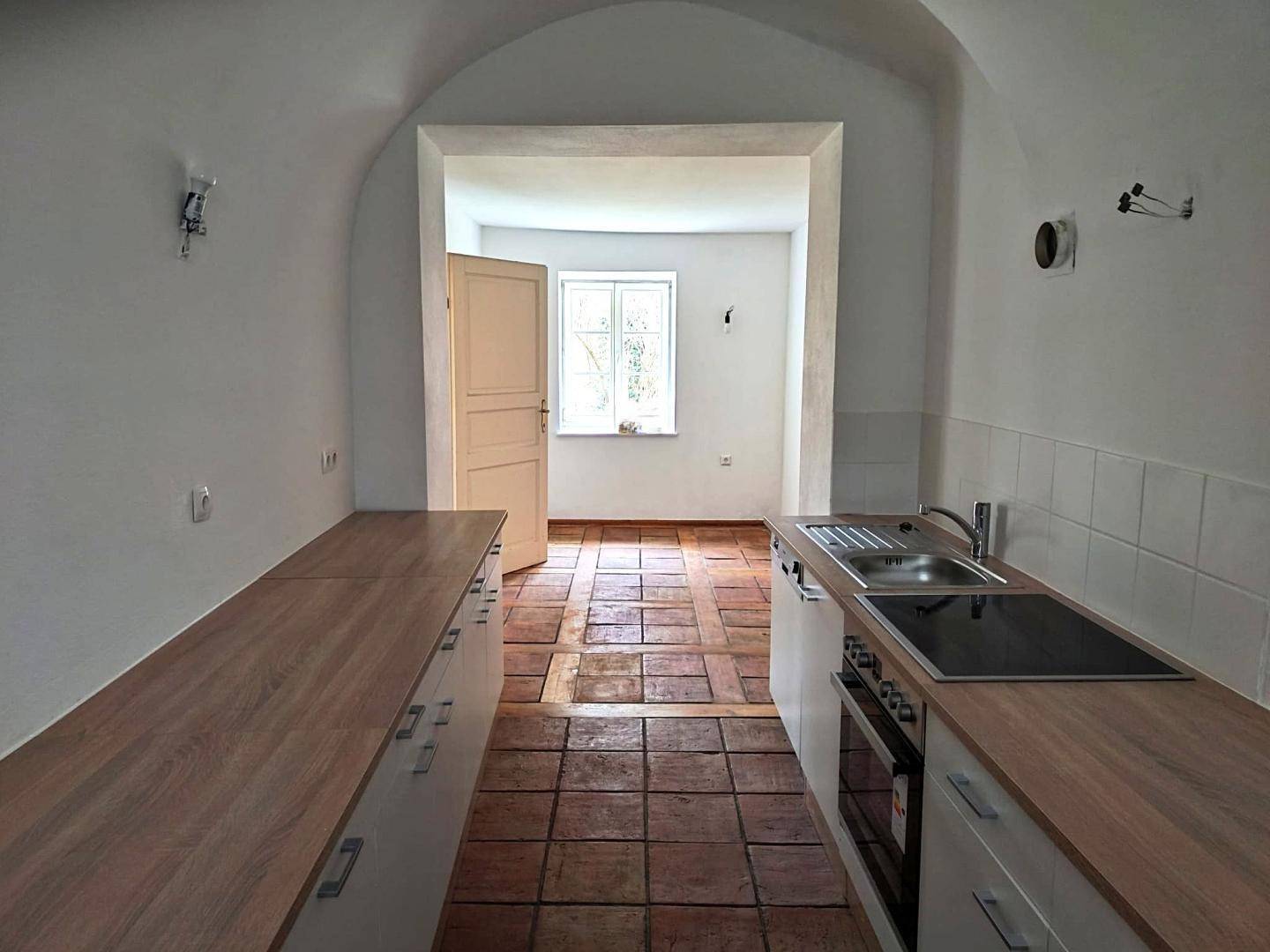 Schmale Küche mit Gewölbedecke, Terrakottafliesen und moderner Einbauküche.