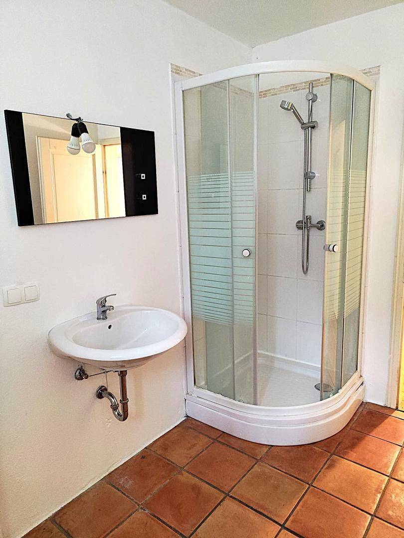 Badezimmer mit Duschkabine, Waschbecken und Terrakottafliesen, in gutem Zustand.