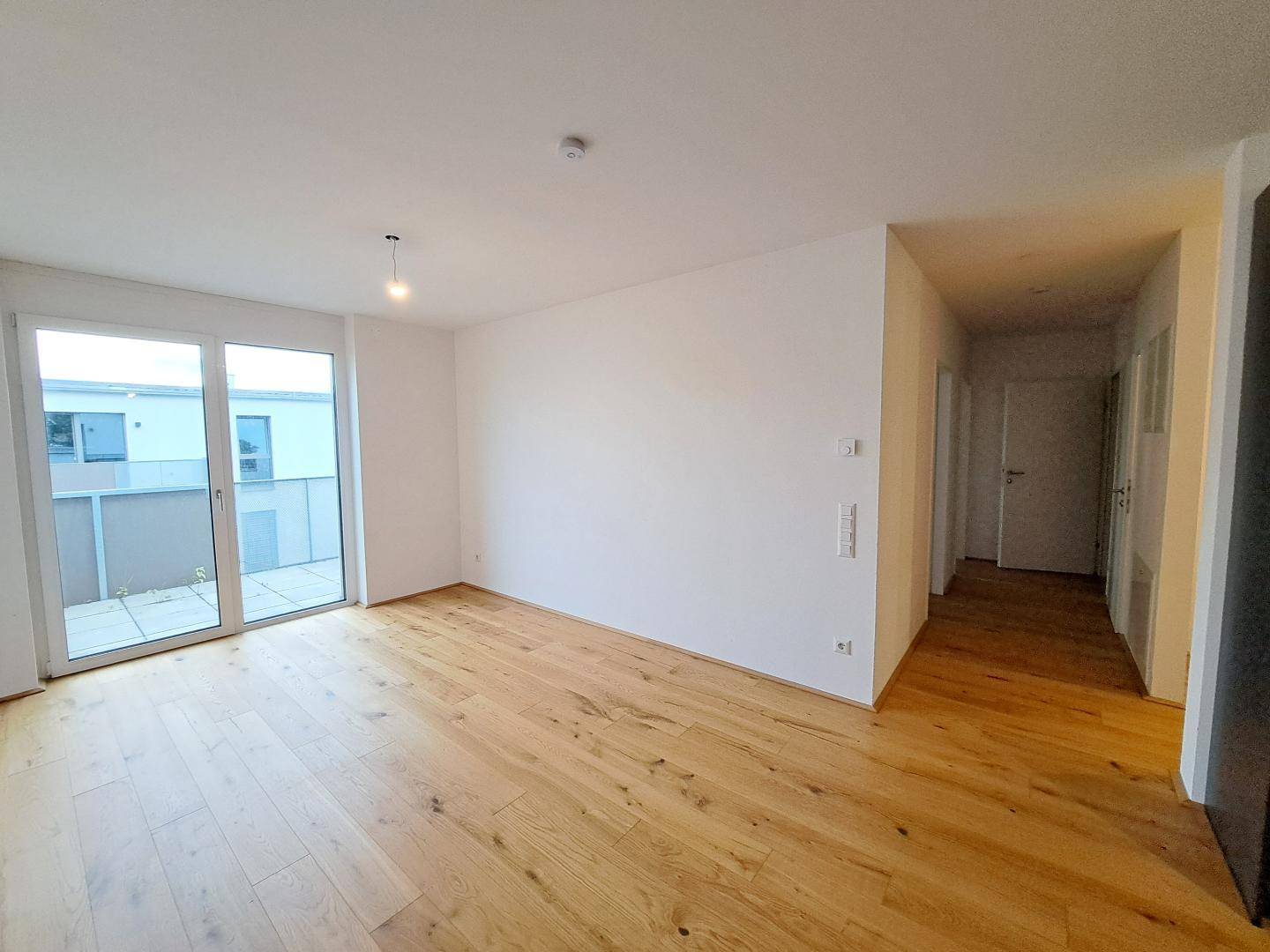 Helles Wohnzimmer mit Holzboden und großzügigem Zugang zu einer Terrasse.