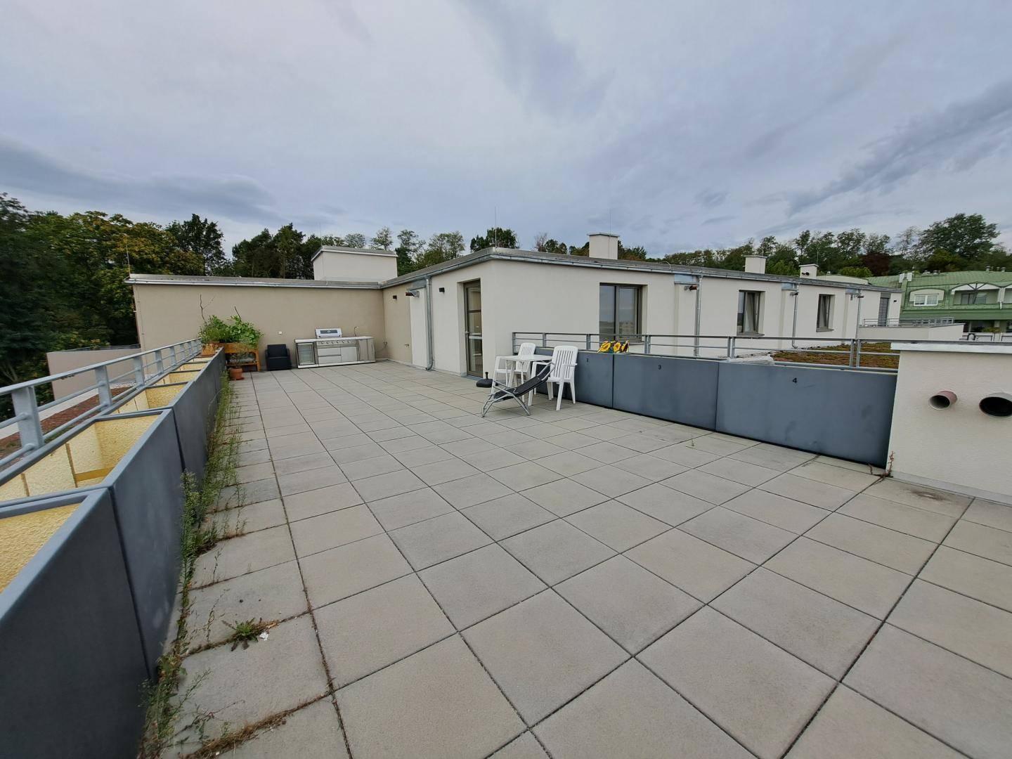 Weitläufige Dachterrasse mit Fliesenboden und einer kleinen Außenküche.