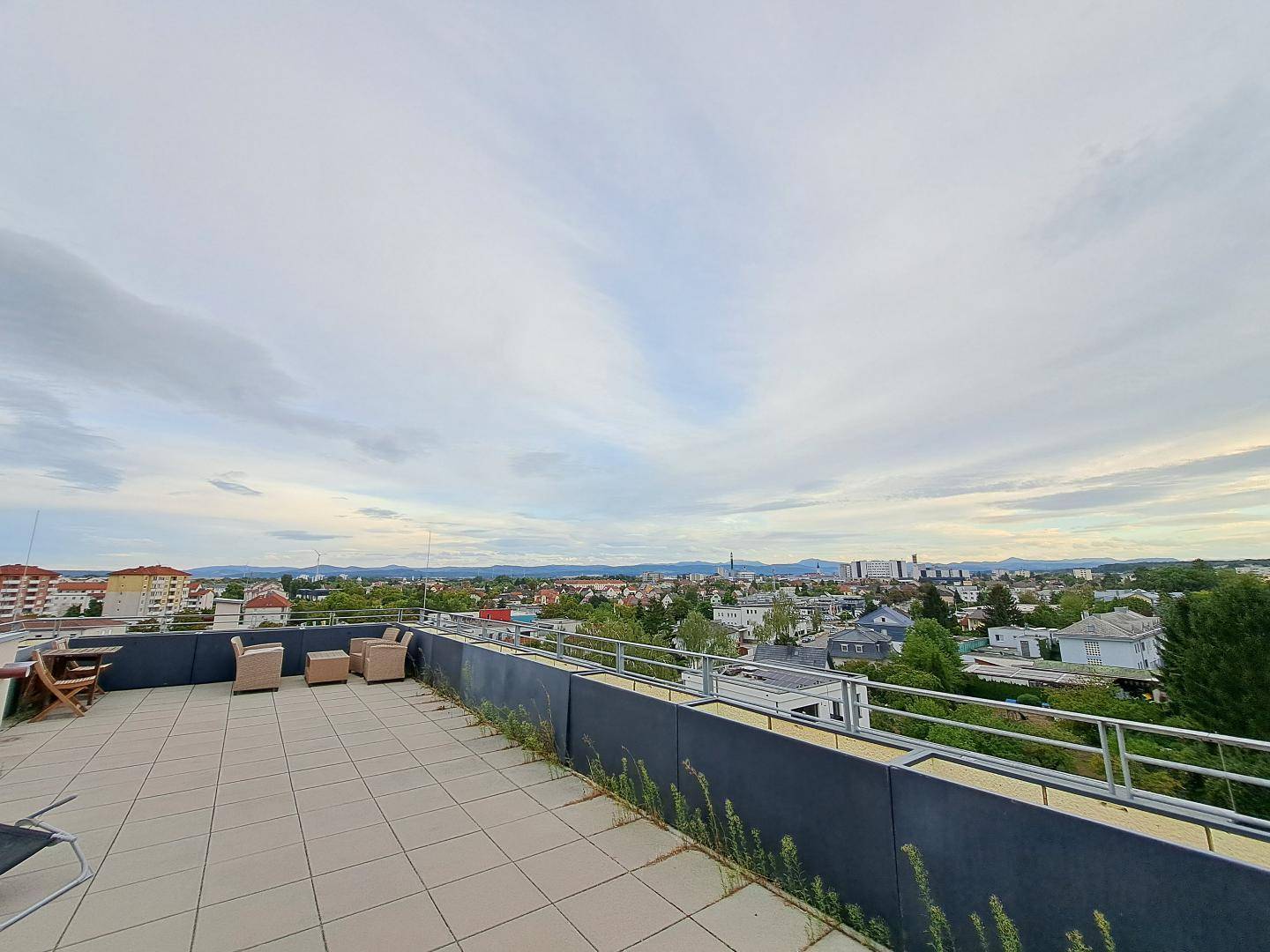 Großzügige Dachterrasse mit Sitzgelegenheiten und weitem Blick über die Stadt und Berge.
