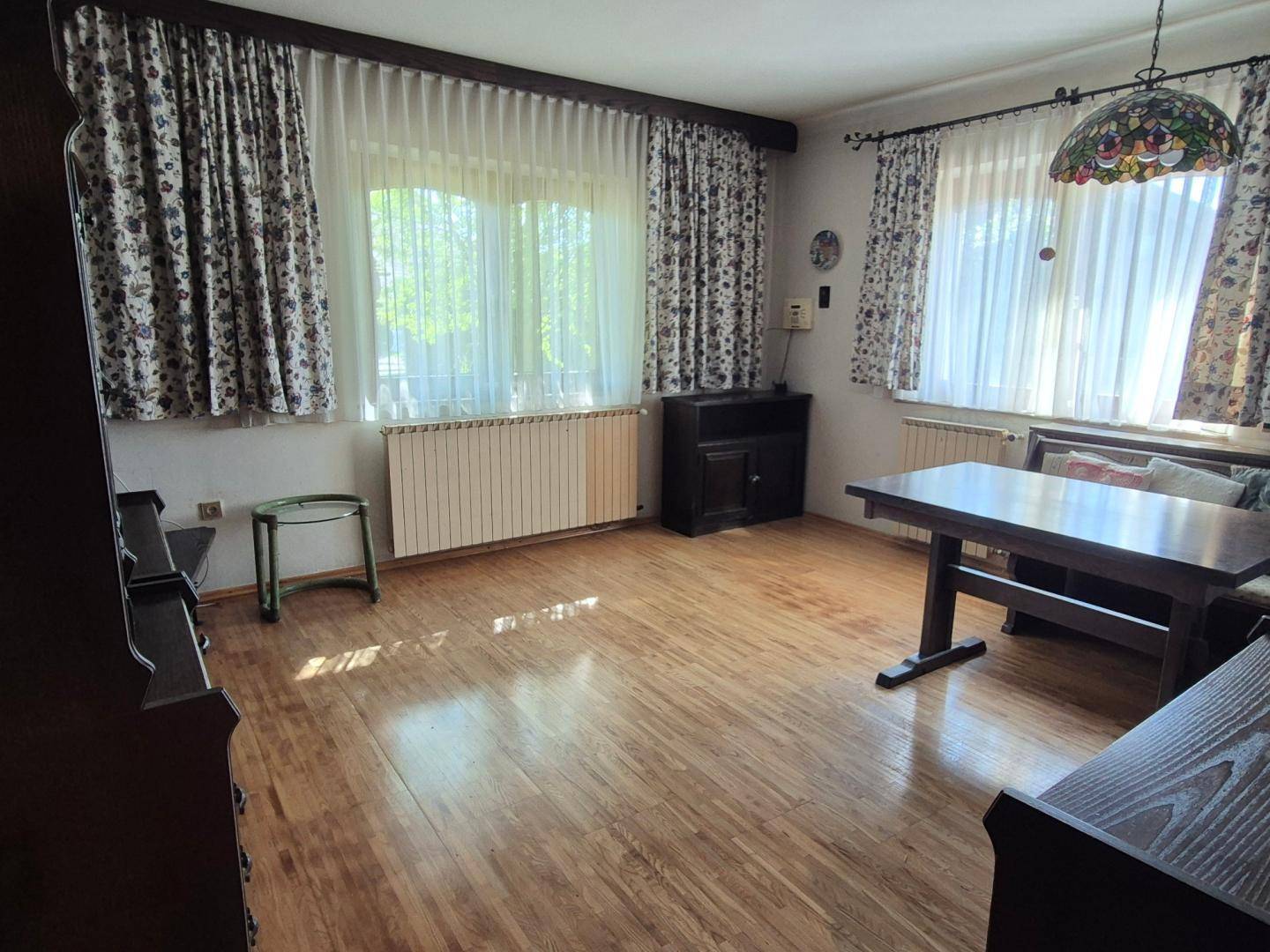 Gemütlicher Essbereich mit Holzboden, traditionellen Vorhängen und viel Tageslicht durch die Fenster.
