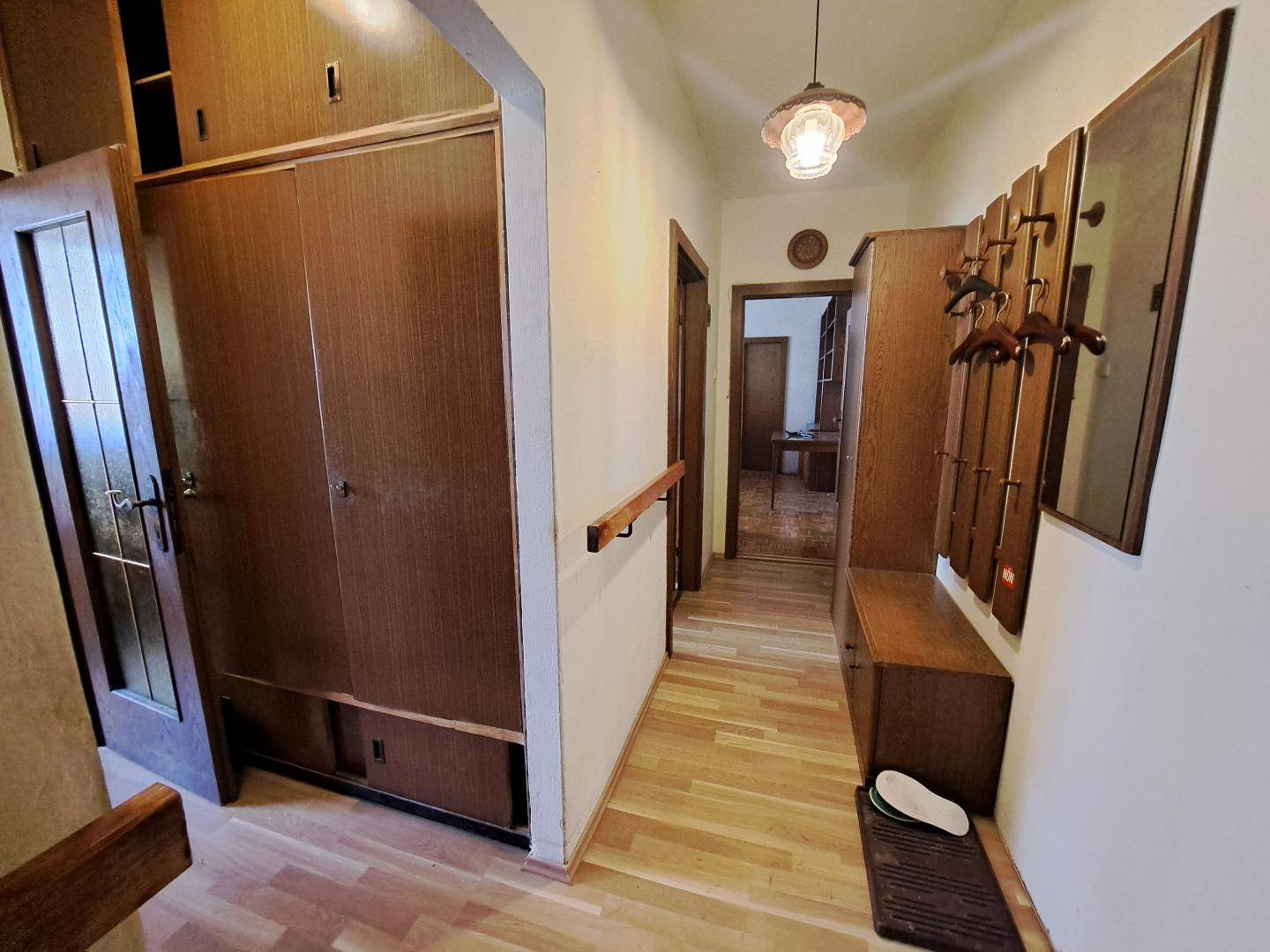 Langer Flur mit Holzschränken, Garderobe und Parkettboden.