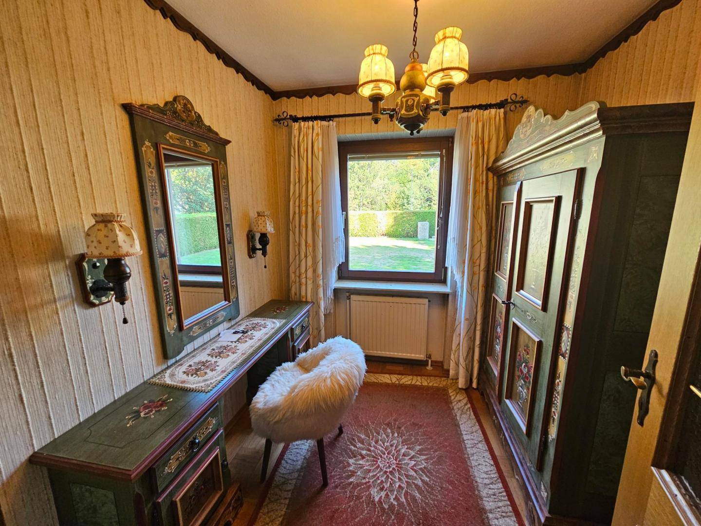 Traditionell eingerichteter Flur mit bemaltem Holzschrank, Spiegel und Blick in den Garten.