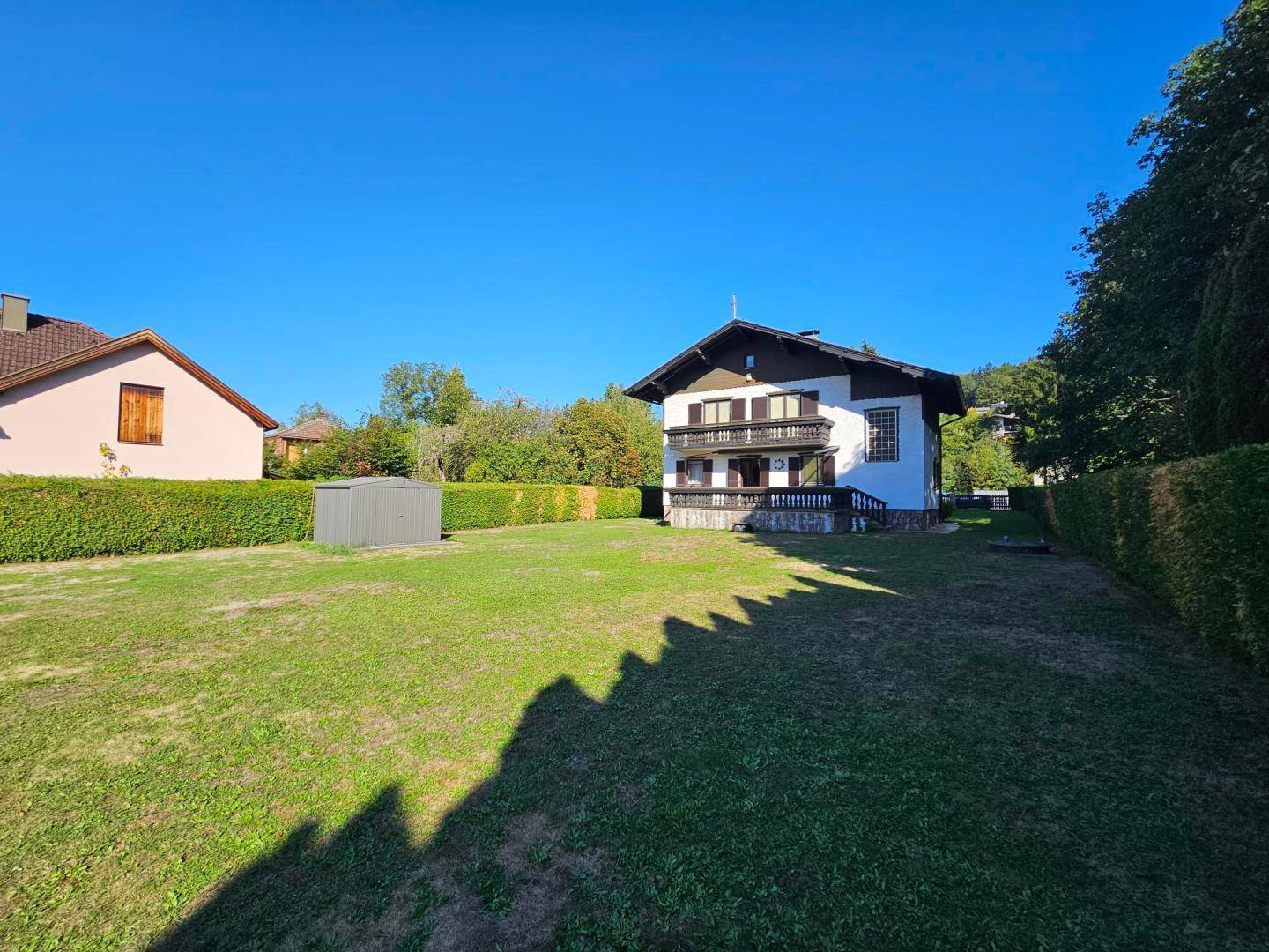 Ansicht des Hauses von der Seite mit großem Garten, Hecke und Geräteschuppen.