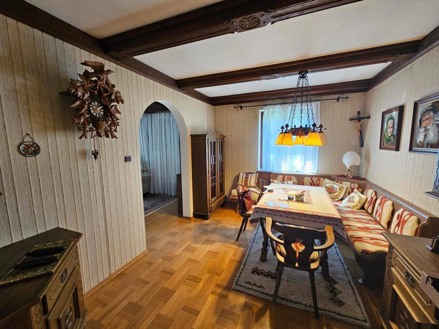 Traditioneller Essbereich mit Eckbank, Holztisch und dekorativer Kuckucksuhr an der Wand.
