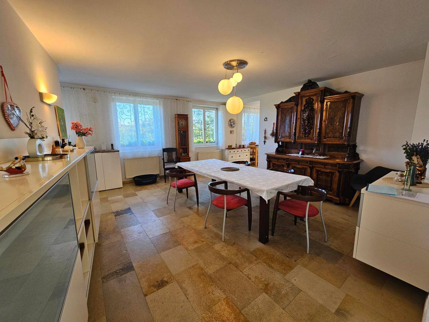 Gemütlicher Essbereich mit traditionellen Holzmöbeln, Steinboden und Blick in den Garten.